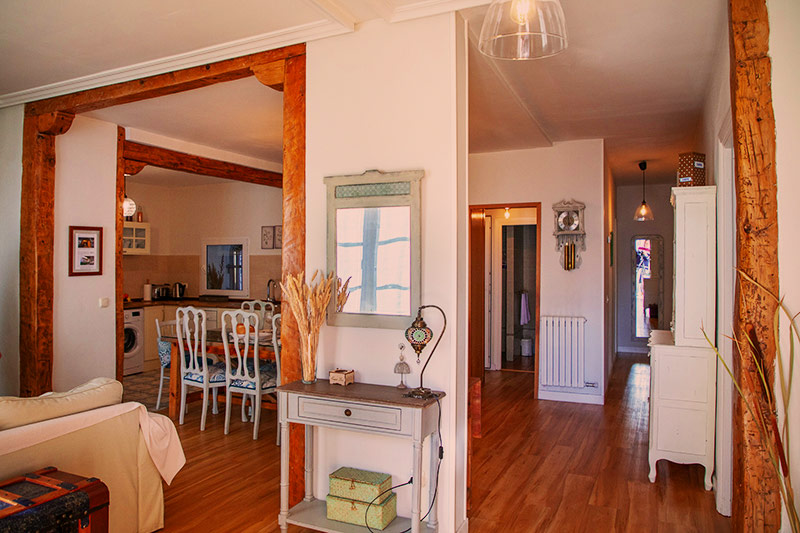 Zona de la entrada cocina y salón con pórticos de madera